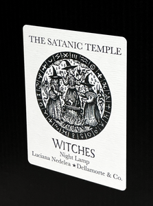 A white rectangular night light plaque featuring black printed text and an illustration. The text reads 'THE SATANIC TEMPLE' at the top, 'WITCHES Night Lamp' below the illustration, and 'Luciana Nedelea * Dellamorte & Co.