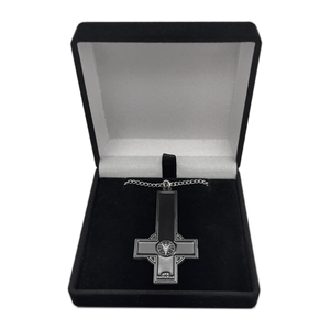 A gothic-style cross pendant necklace with a black enamel center and silver-toned metal borders, displayed inside an open black velvet jewelry box on a white background.