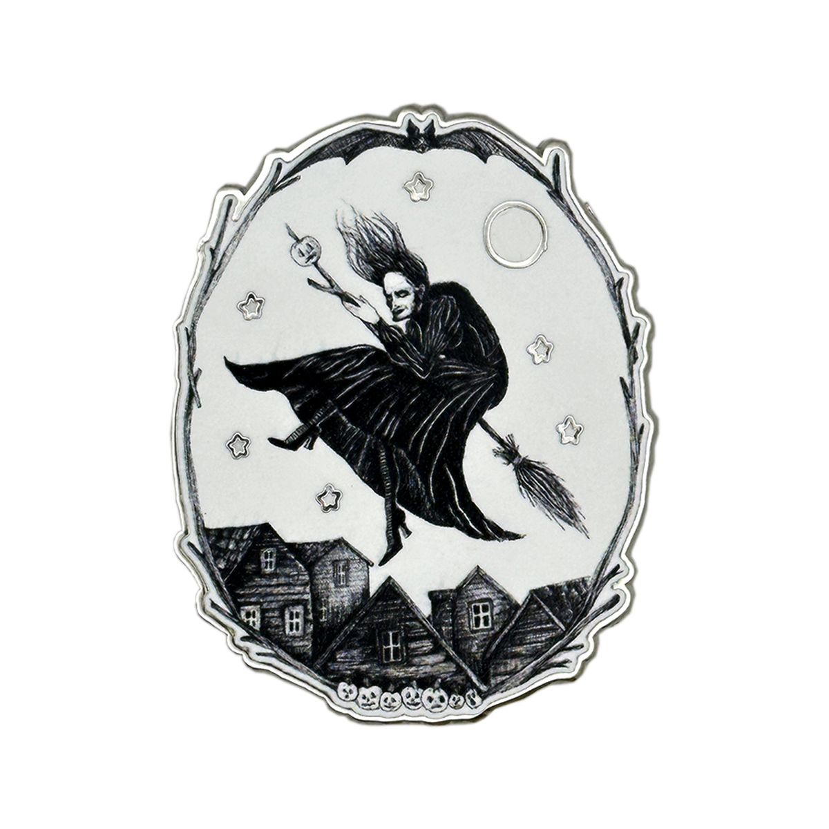 A silver-toned and white oval pendant or featuring a black illustration of a witch riding a broomstick over small houses under a full moon, with stars around the scene. Glows in the dark 